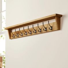 a wooden coat rack with six hooks on it's sides, hanging from the wall