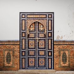 an intricately designed door in front of a brick wall