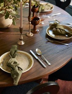 a wooden table topped with plates and silverware