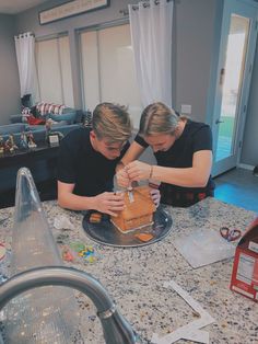 two people are building a gingerbread house