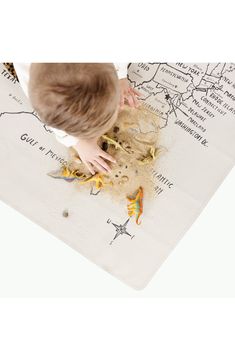 a young boy playing with sand on a map