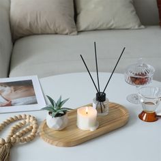 two candles are sitting on a tray next to a photo and other items that include an air plant