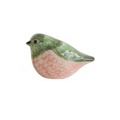 a small green and pink bird sitting on top of a white surface