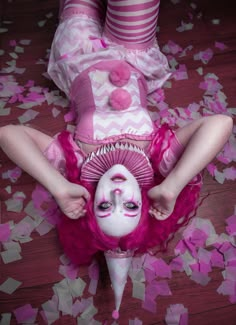 a woman laying on the floor with her face painted pink and white, surrounded by confetti