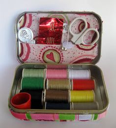 an open tin can with spools of thread and scissors