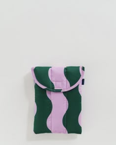 a green and pink bag sitting on top of a white wall