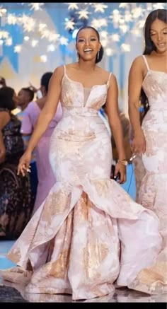 two women in dresses walking down the runway