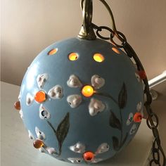 a blue ball with flowers on it is hanging from a chain