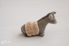 a small knitted toy donkey with a sweater on it's back, standing upright