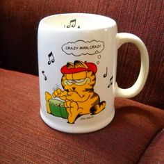 a white coffee mug with a cartoon cat on it's side and music notes coming out of its mouth