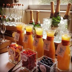 a table topped with lots of bottles of wine and glasses filled with fruit next to each other