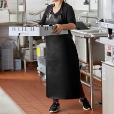 a woman in an industrial kitchen holding a pizza box