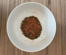 a white bowl filled with spices on top of a wooden table