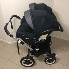 a black stroller sitting on top of a tile floor next to a white wall