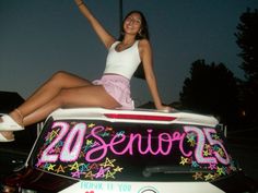 a woman sitting on the back of a car with her arms up in the air