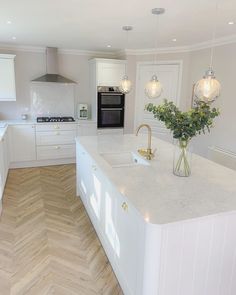 a large kitchen with white cabinets and wood flooring on the walls, along with an island in the middle