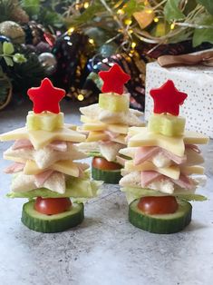 small sandwiches made from cucumbers and cheese with red stars on top, sitting next to a christmas tree