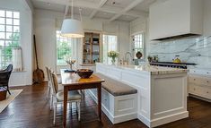 a large kitchen with white cabinets and wood flooring, along with a dining room table