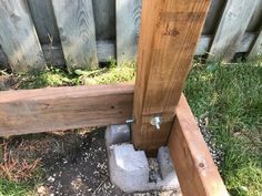 a wooden bench sitting in the grass next to a fence with an opening on it