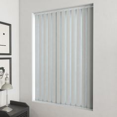 an empty room with white walls and blinds on the window sill, next to a lamp