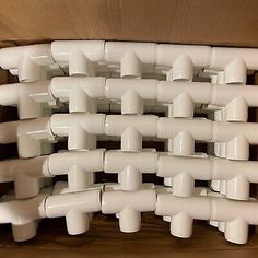 a box filled with lots of white plastic pipes