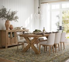 a dining room table with chairs and vases on top of it in front of a window