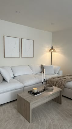 a living room with white couches and two lamps on the side of the wall