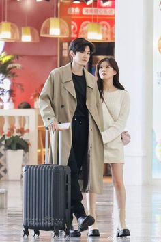 a man and woman standing next to each other with luggage