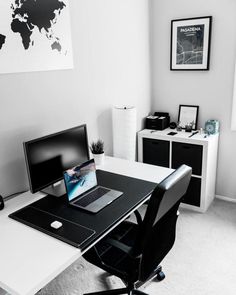 a black and white photo of a desk with a lap top on it in front of a world map