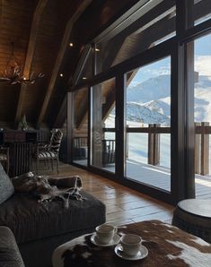 a living room filled with furniture and a large window overlooking the snow covered mountain range