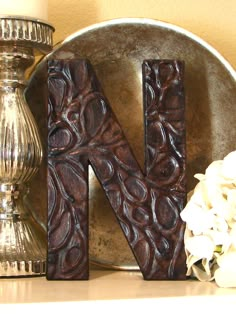 the letter n is made out of wood and sits on a table next to a candle