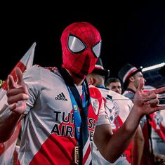 a man wearing a spider - man mask and holding a cell phone in his hand