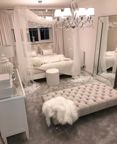 a bedroom with white furniture and chandelier hanging from the ceiling in front of a mirror