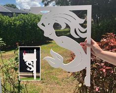 a person holding up a cutout of a dragon in front of some bushes and trees