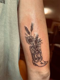 a tattoo on the arm of a person with boots and flowers