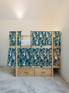 the bunk bed is made up with two sets of drawers and a curtain over it