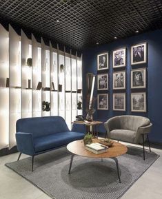 a living room with blue walls and pictures on the wall, two chairs and a coffee table