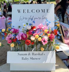 there is a sign that says welcome to the baby shower and flowers in vases