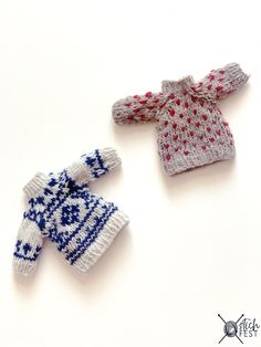 two knitted sweaters sitting next to each other on top of a white surface