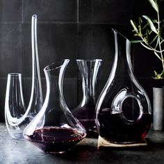 four glass vases sitting on top of a table next to a potted plant