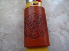 a leather lighter case with a fire department emblem on the front and back side, sitting on a marble surface