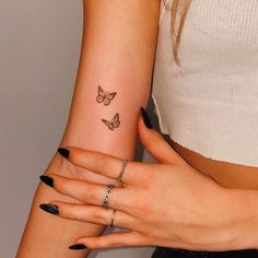 two women with matching tattoos holding each other's hands and one has a butterfly tattoo on her left arm