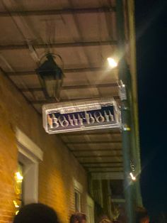 people are standing under a sign that says bourbon on the side of a brick building