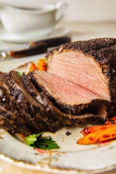 a piece of roast beef on a plate with carrots and parmesan cheese