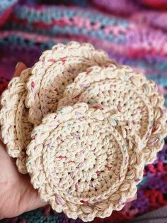 a hand holding three crocheted rings on top of a multicolored blanket