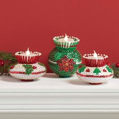 three decorated christmas candles sitting on top of a mantle