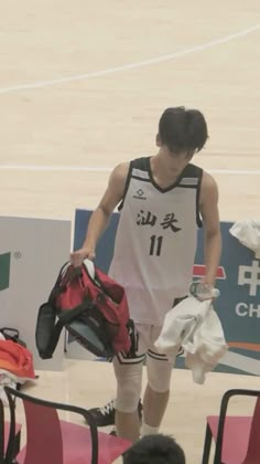 a basketball player is walking on the court with his back to the camera while holding some sports gear