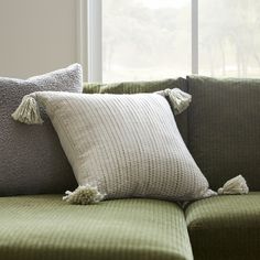 a green couch with two pillows on it and a window in the backround