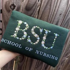 someone is holding up a small purse with the word boo school of nursing on it