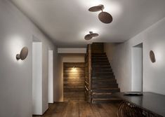 an empty room with wooden floors and ceiling fan lights on the wall, along with stairs